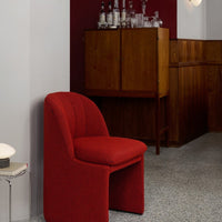 Red textured chair against a maroon wall and wooden furniture, creating a modern and warm atmosphere.