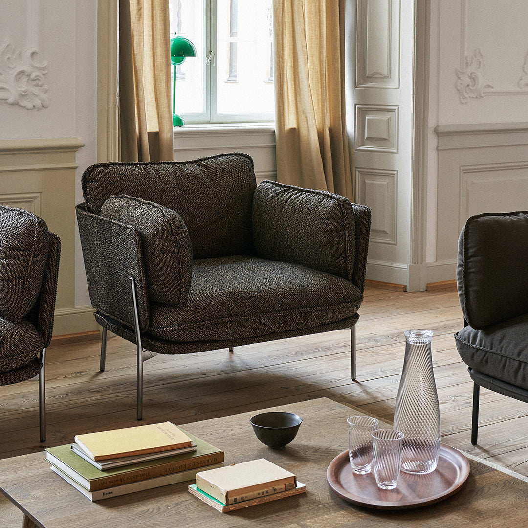 Stylish dark gray armchair with textured upholstery and sleek metal legs, complementing a light and airy room.