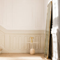 Elegant gold-accented mirror with soft beige tones and a minimalistic design against a bright, neutral backdrop.