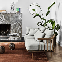 Light gray upholstery, wooden frame, earthy brown rug, and patterned marble details create a modern, stylish living space.