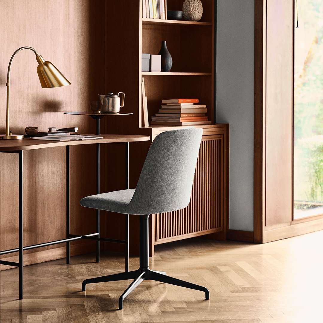 Gray upholstered chair with a sleek design, complemented by a black metal base and a rich wood backdrop.