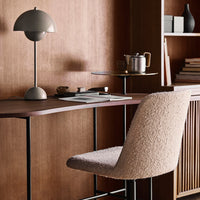 Soft beige textured chair against warm wood tones, complemented by sleek black and gray accents in a modern workspace.