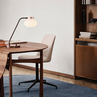 Elegant wooden desk with soft beige chair, layered on a textured blue rug against a neutral wall.