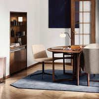 "Modern desk setup featuring a light beige chair, muted gray rug, and natural wood tones in a stylish workspace."
