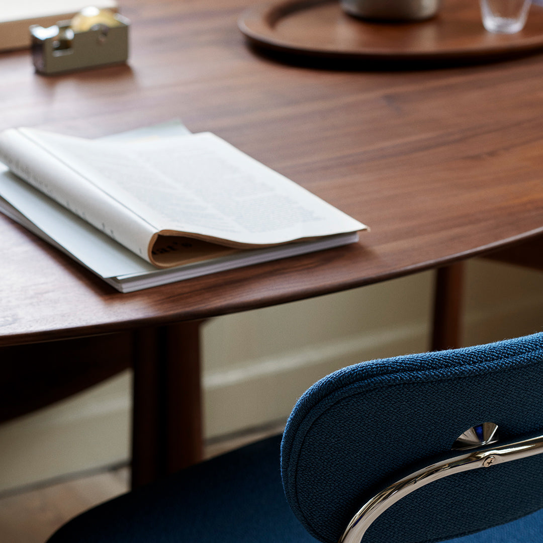 Blue upholstered chair beside a sleek wooden desk, with light gray and white papers on the surface, creating a modern aesthetic.