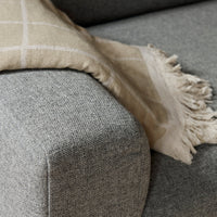 Soft beige blanket with a grid pattern draped over a textured gray sofa. Perfect for cozy decor accents.
