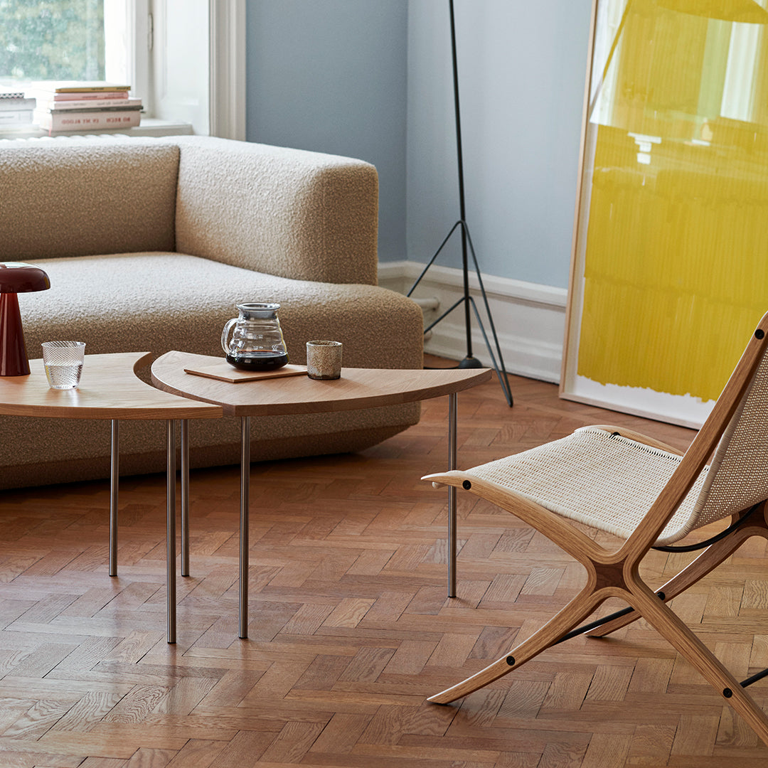 Modern living room featuring beige sofa, yellow art piece, and wood coffee table with elegant curves on a wooden floor.