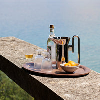 Elegant silver barware set on a rich wooden tray, featuring clear glasses and vibrant yellow lemons against a serene blue backdrop.