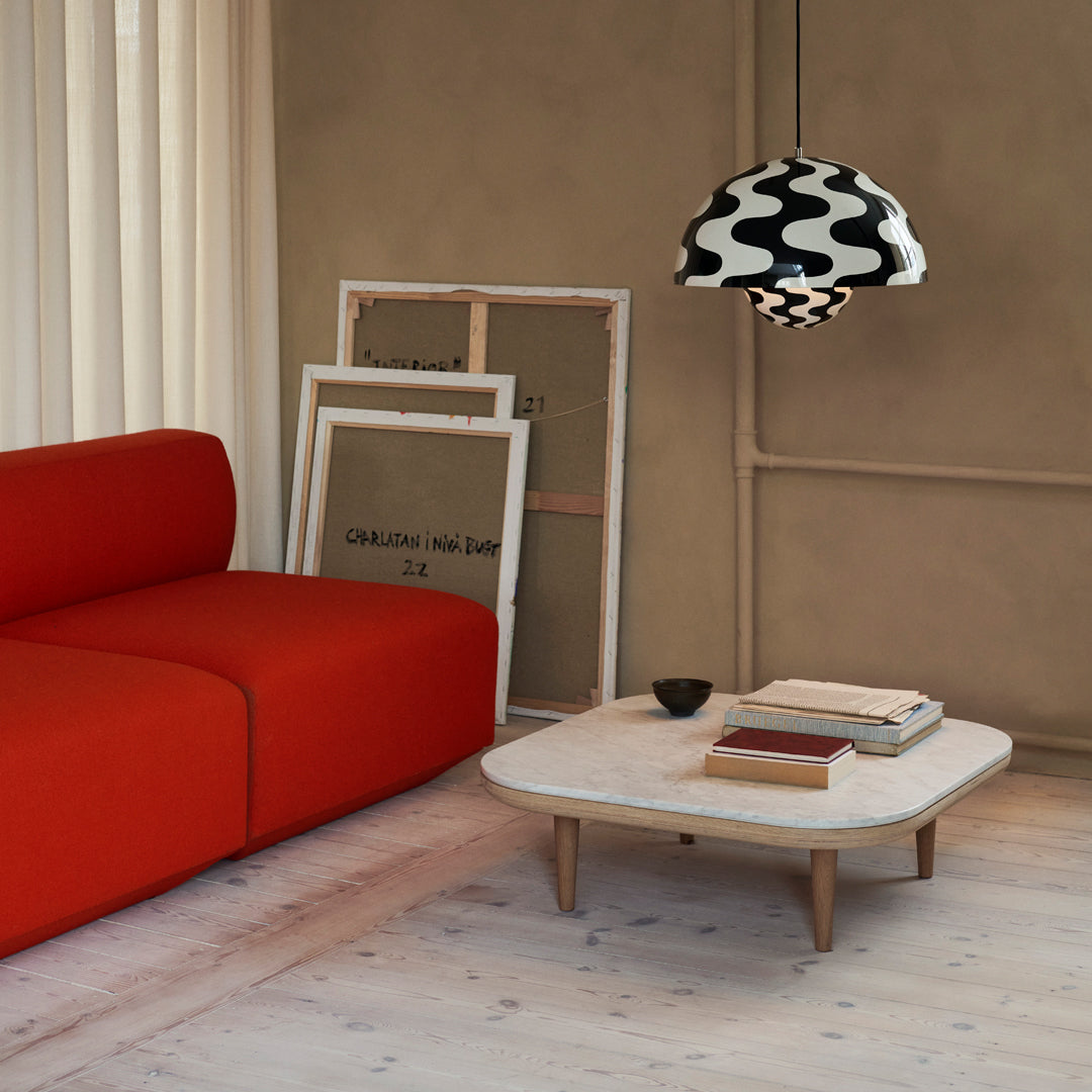 "Vibrant red couch with a stylish black and white patterned lampshade above a light wood coffee table."