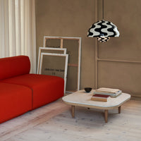 "Vibrant red couch with a stylish black and white patterned lampshade above a light wood coffee table."