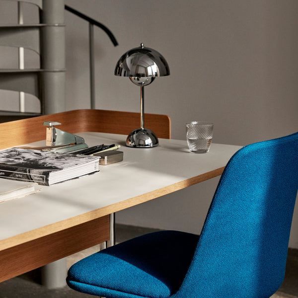 Bright blue chair against a light wood desk, featuring silver accents and soft gray textures in a modern setting.