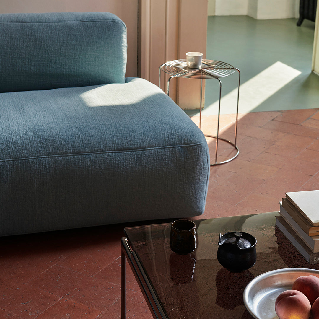 Soft blue couch with a textured fabric, set against warm terracotta flooring and modern metal accents.