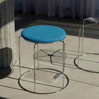 Blue upholstered stool with a sleek chrome base and circular design, perfect for modern decor.