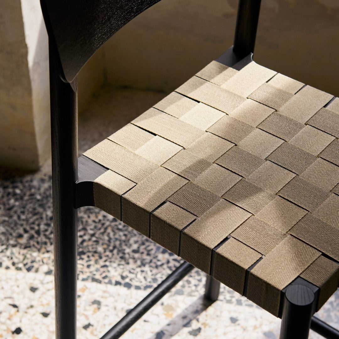 Woven chair seat in subtle beige tones with a textured pattern against a sleek black wooden frame.