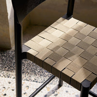 Woven chair seat in subtle beige tones with a textured pattern against a sleek black wooden frame.