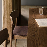 Wooden chair with a textured, dark purple seat and an oak table featuring a rich, natural grain pattern.