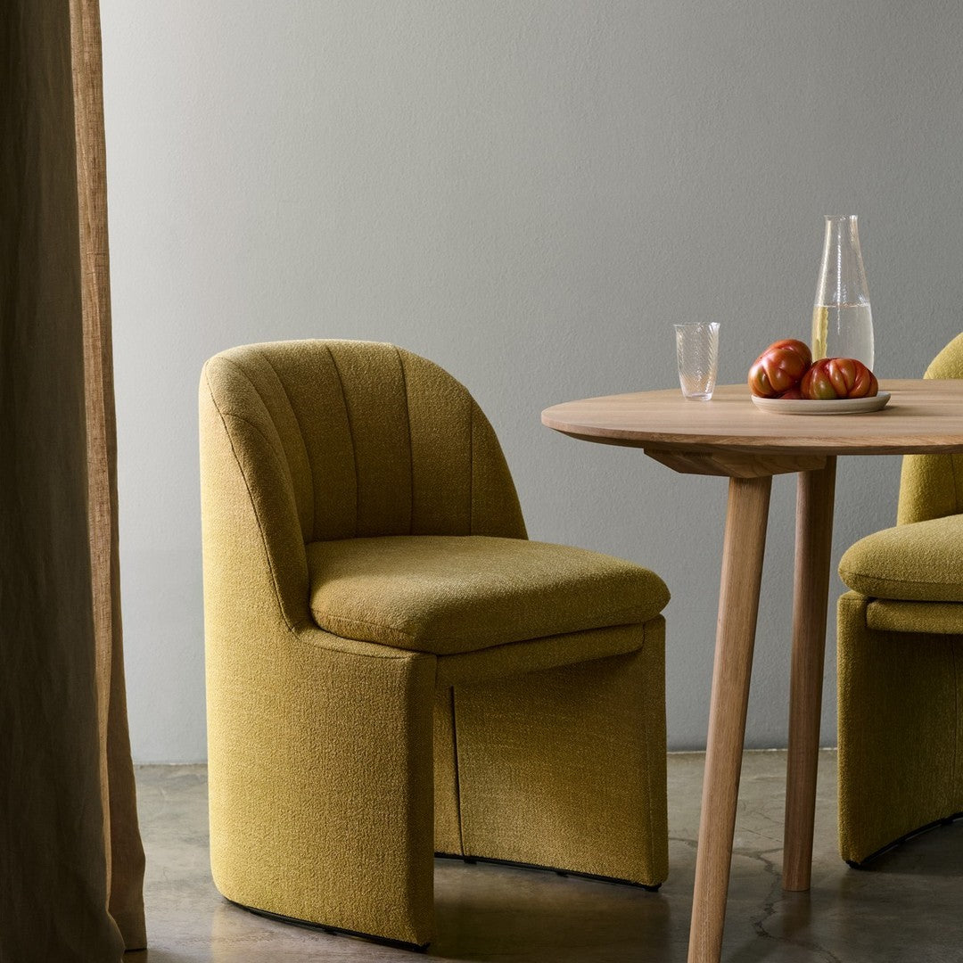 Yellow textured chairs with curved backs and a natural wood table, accented by vibrant red apples.
