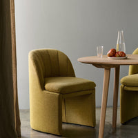Yellow textured chairs with curved backs and a natural wood table, accented by vibrant red apples.