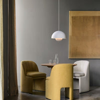 Modern dining area with yellow and cream chairs, circular wood table, and a white pendant light against gray walls.