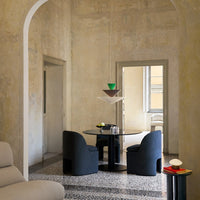 Modern dining area featuring a black round table, dark blue chairs, and a colorful pendant light with geometric patterns.