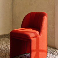 Red upholstered chair with a textured pattern, featuring subtle lines and a stylish, modern design.