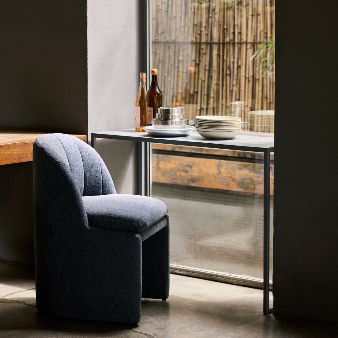 Stylish gray upholstered chair with ribbed pattern, set against a minimalist backdrop with earthy tones and natural light.