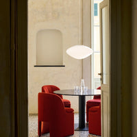 Red textured chairs surround a sleek black round table, complemented by a contemporary white pendant light.