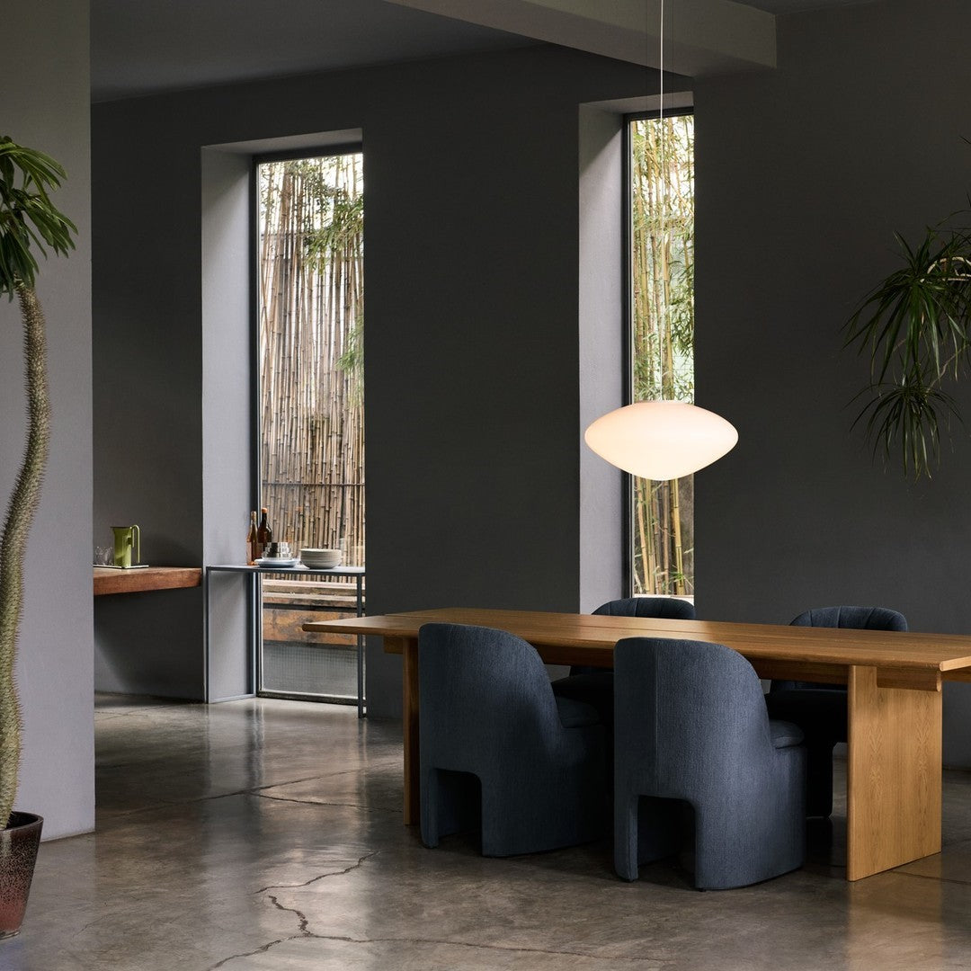 Modern dining area featuring dark blue upholstered chairs, natural wood table, and warm grey walls.