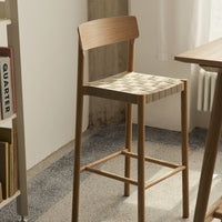 Light wood bar stool with a woven, checkered pattern in neutral tones, adding a modern touch to any space.