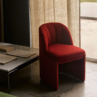 Red upholstered chair with textured pattern, featuring curved lines and a modern design against a neutral backdrop.