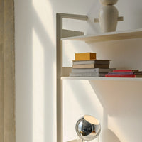 Elegant beige shelves with minimalist decorative items in warm yellow, gray, and pink tones against a bright, sunlit wall.