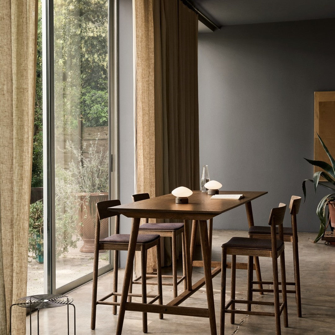 Warm beige curtains, muted grey walls, dark wood furniture, and deep blue chair upholstery create a cozy, modern dining space.