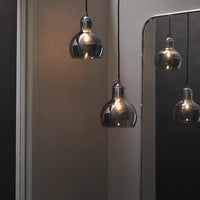 Modern black and clear glass pendant lights with warm glowing bulbs, adding a sleek, industrial touch.