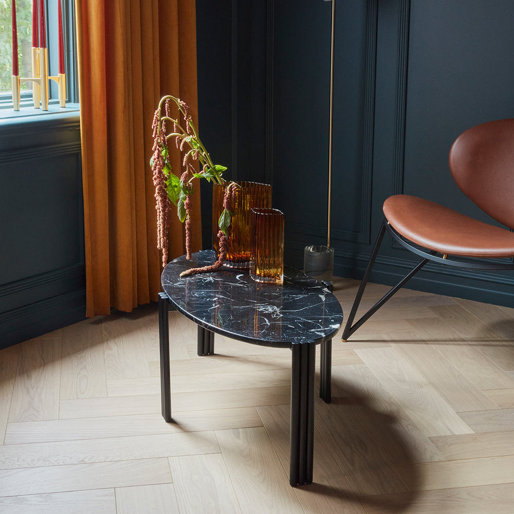 Black marble tabletop with sleek black legs, contrasted by warm amber vases and rich gold curtains. Stylish modern decor.