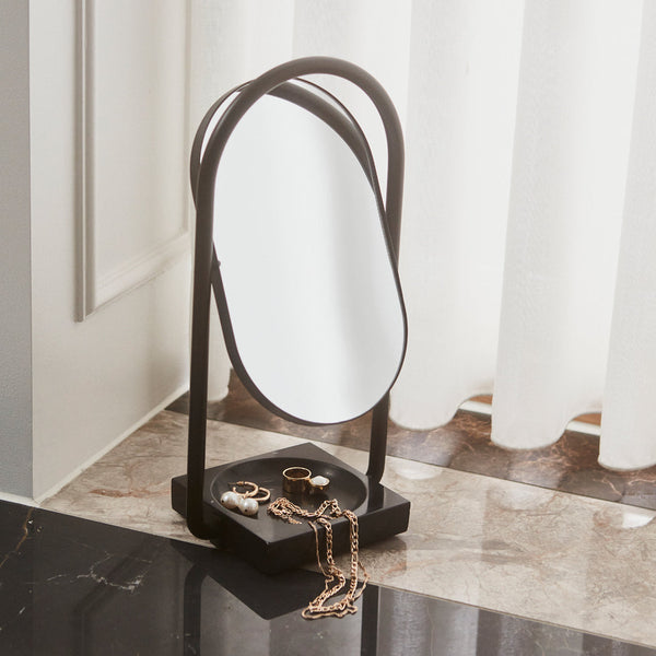 "Modern black metal mirror with sleek oval shape and minimalist design, featuring a smooth reflective surface."