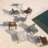 Various modern chairs in green, gray, brown, and white, casting unique shadows by a poolside. 