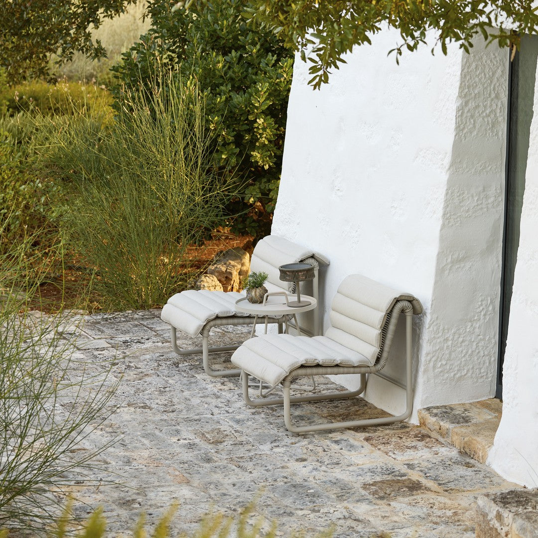 "Neutral-toned outdoor lounge chairs with sleek, minimalistic design against a textured stone patio."