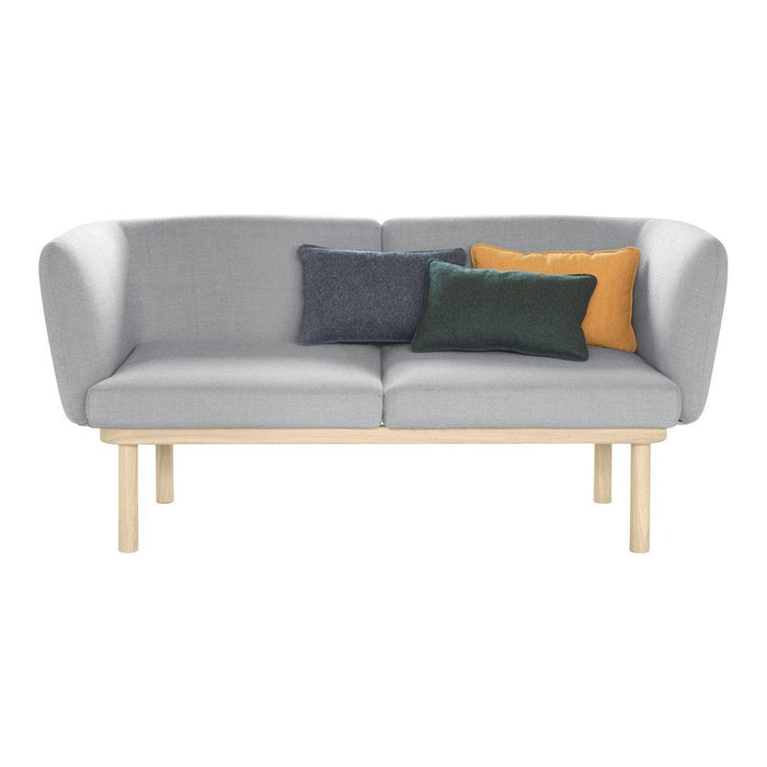 Grey two-seater sofa with light wood legs and colorful accent pillows in navy, green, and mustard yellow.