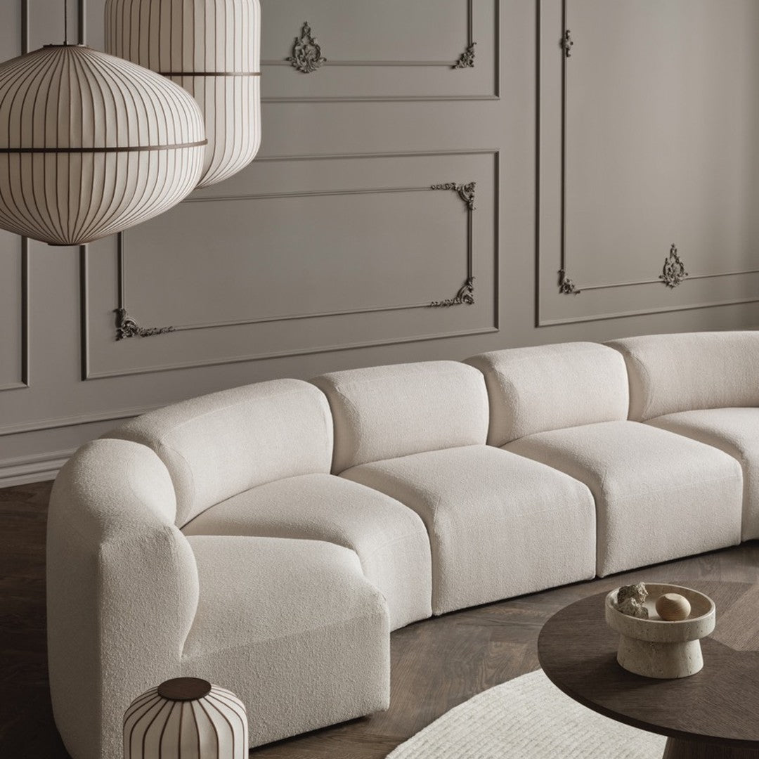 "Modern curved sofa in soft beige fabric, complemented by elegant cream and brown accents in a stylish interior setting."