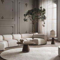 Beige sectional sofa, natural wood table, soft white rug with subtle patterns, and neutral-toned walls and decor.