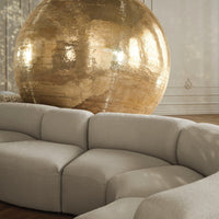 Beige curved sofa with a textured finish, set against a shimmering gold disco ball backdrop.