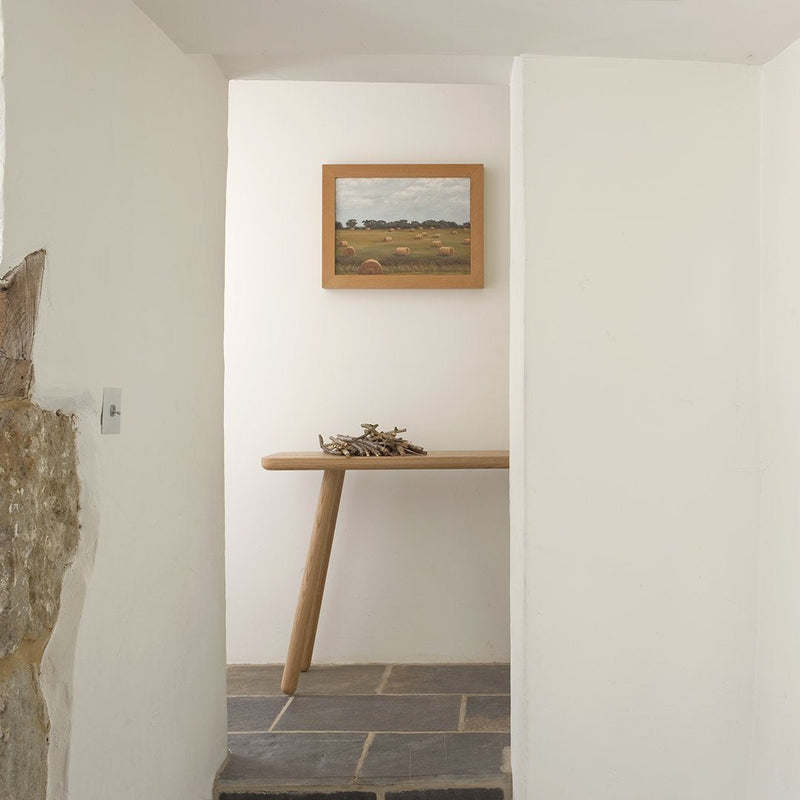 Minimalist entryway with white walls, natural wood table, and earthy stone flooring for a serene aesthetic.