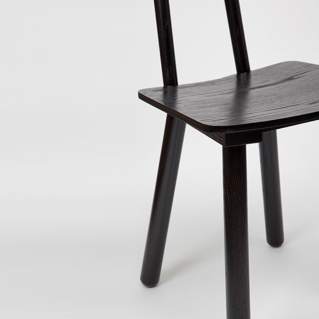 Black wooden chair with a minimalist design, featuring a smooth, natural grain pattern and sleek, straight legs.