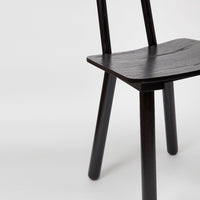 Black wooden chair with a minimalist design, featuring a smooth, natural grain pattern and sleek, straight legs.