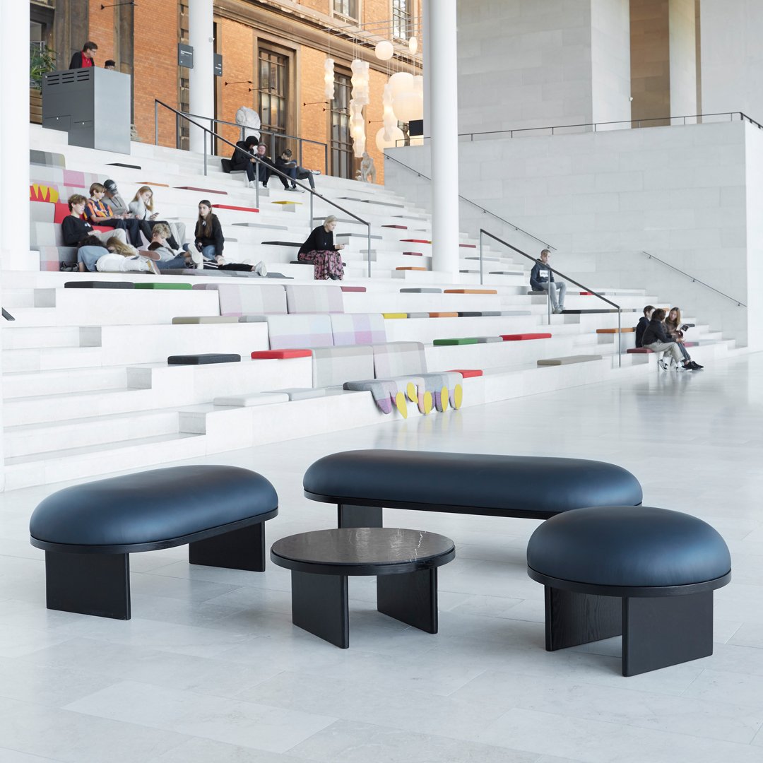Modern furniture set featuring deep blue upholstery and sleek black bases, with smooth, rounded shapes and minimalistic design.