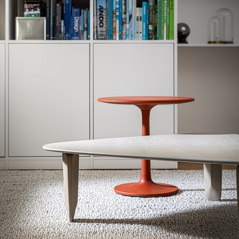 Modern coffee tables featuring a sleek gray top and vibrant orange base on a textured rug. Perfect for contemporary decor.