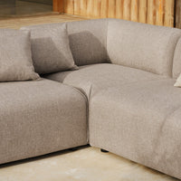 Tan fabric sectional sofa with soft, textured upholstery and matching cushions. Modern, minimalist design.