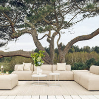 Beige sectional sofa with smooth lines, soft textures, and minimalistic design, set against a natural outdoor backdrop.
