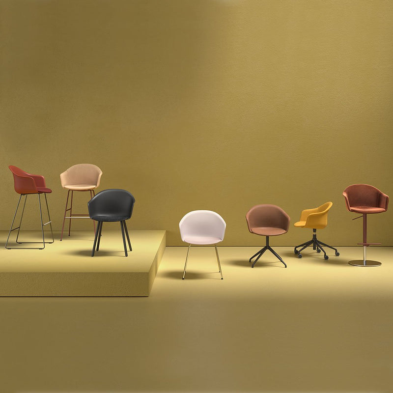 Variety of stylish chairs in shades of blue, pink, brown, mustard, and burgundy against a soft yellow backdrop.