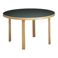 Round table with a sleek black top and natural wood legs, perfect for modern decor.